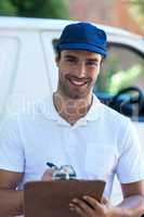 Portrait of happy delivery man writing in clipboard