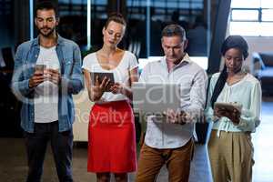 Team of colleagues using mobile phone, digital tablet and laptop