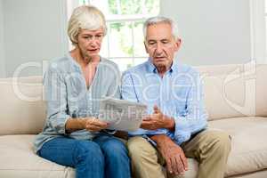 Sad senior couple reading document at home