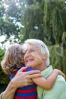 Happy grandfather hugging grandson at yard