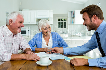 Happy couple with agent while sitting at table
