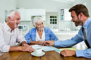 Happy couple with agent while sitting at table