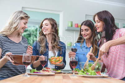 Friends holding glass of red wine while having meal