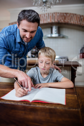 Father helping son with his homework in kitchen