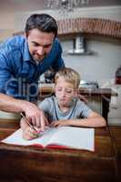 Father helping son with his homework in kitchen