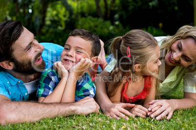 Happy parents lying with children in yard