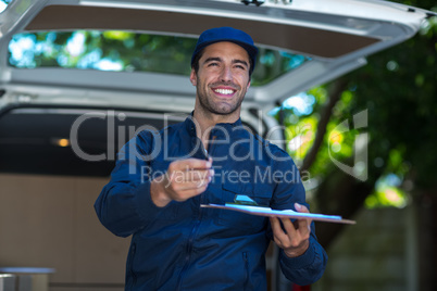 Smiling delivery person giving clipboard for signature