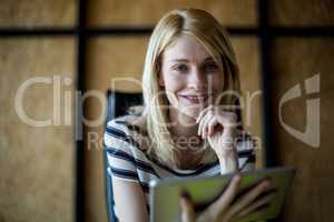 Young woman holding digital tablet smiling at camera