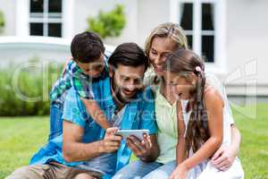 Happy family looking into mobile phone at yard