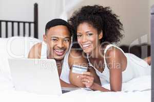 Happy couple shopping online through laptop using credit card