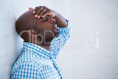 Upset man with eyes closed and hand on the forehead leaning agai
