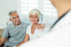 Smiling senior couple with doctor at home