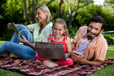 Family using technologies relaxing in yard