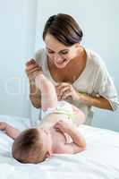 Playful mother with baby boy lying on bed