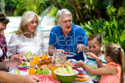 Granparents having breakfast with family at yard