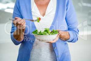 Mid section of senior woman eating salad