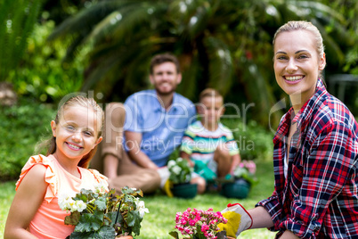 Smiling mother and daughter with flower pots in yard