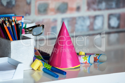 Party horn, birthday hat, pen holder and spectacle on desk