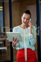 Woman looking at digital tablet while talking on phone