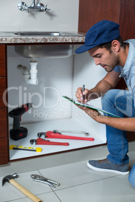 Man writing on clipboard with work tools