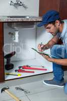 Man writing on clipboard with work tools