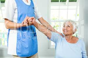 Smiling senior woman exercising with nurse