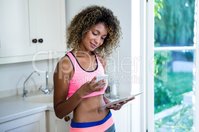 Young woman using phone and digital tablet in kitchen Young woman using phone and digital tablet in kitchen
