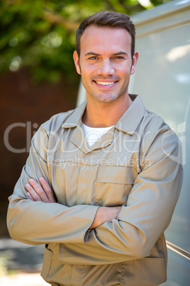 Confident delivery man standing with arms crossed