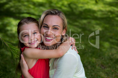 Portrait of smiling mother with daughter in yard