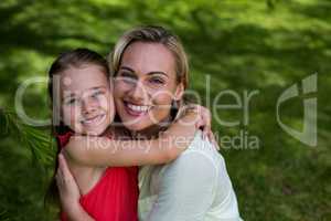 Portrait of smiling mother with daughter in yard