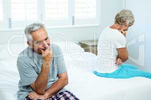 Sad senior man and woman sitting on bed