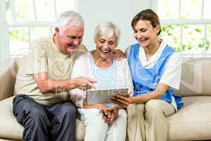 Happy nurse and senior adults holding digital tablet