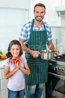 Happy father and daughter preparing food in kitchen