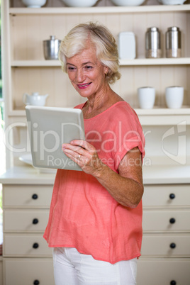 Senior woman using digital tablet in kitchen