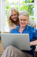 Senior couple using laptop while sitting on at home
