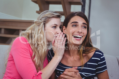 Young woman whispering a secret to her friend