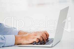 Mid-section of businessman working on laptop