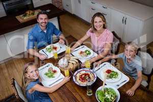 Portrait of happy family having meal in kitchen