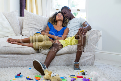 Couple embracing while sitting on sofa in living room