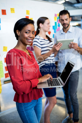 Young woman holding laptop smiling at camera