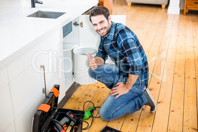 Man fixing kitchen sink giving thumbs up