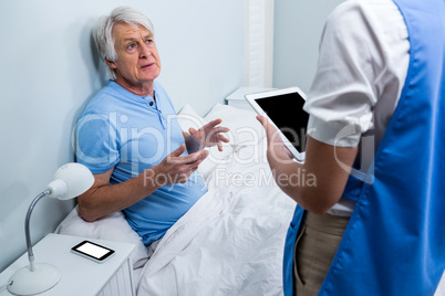 Nurse discussing with senior man at hospital