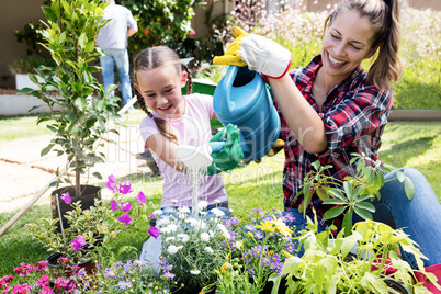 Mother and daughter watering the plants in the garden