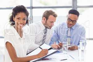 Portrait of businesswoman writing on file in office