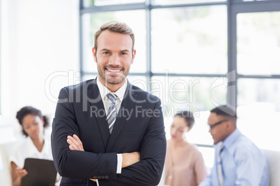 Happy businessman standing with arms crossed