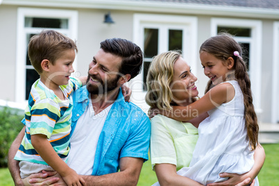 Happy parents carrying children in yard