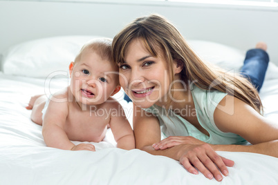 Happy mother and son lying on bed at home