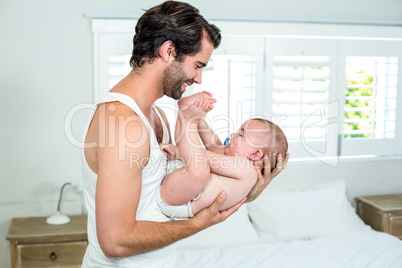 Father playing with son by bed