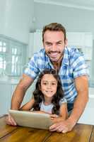 Father and daughter using digital tablet at home