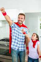 Father and daughter in superhero costume with hand raised